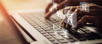 a men is typing on laptop and shopping symbol running over it