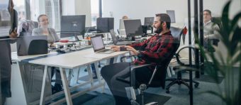 employees sitting on their desks with a laptop in front of them