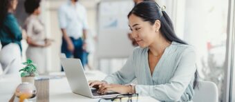 a woman sitting at a table using a laptop computer