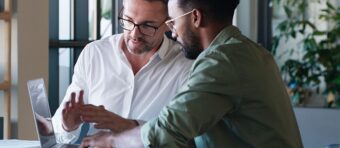 two men are looking at a laptop screen